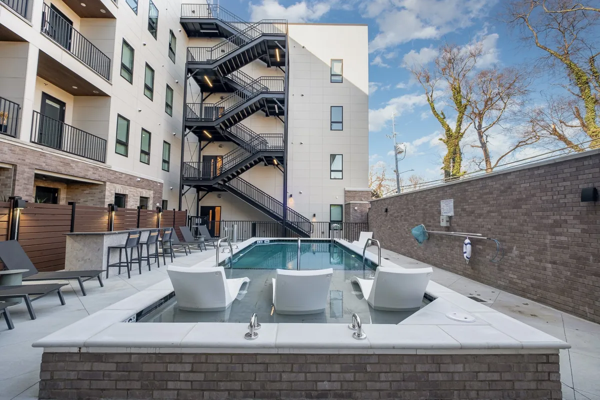 A relaxing outdoor swimming pool area with comfortable seating and a staircase, set in a tranquil environment. The setting feels inviting for downtime and socializing after a busy day.