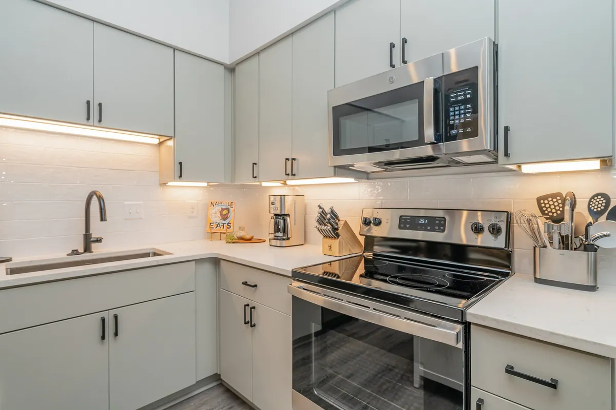 A modern kitchen featuring stainless steel appliances, smooth countertops, under-cabinet lighting, and ample storage with wall-mounted cabinets. The space is organized and functional, inviting for group meal prep or casual gatherings.