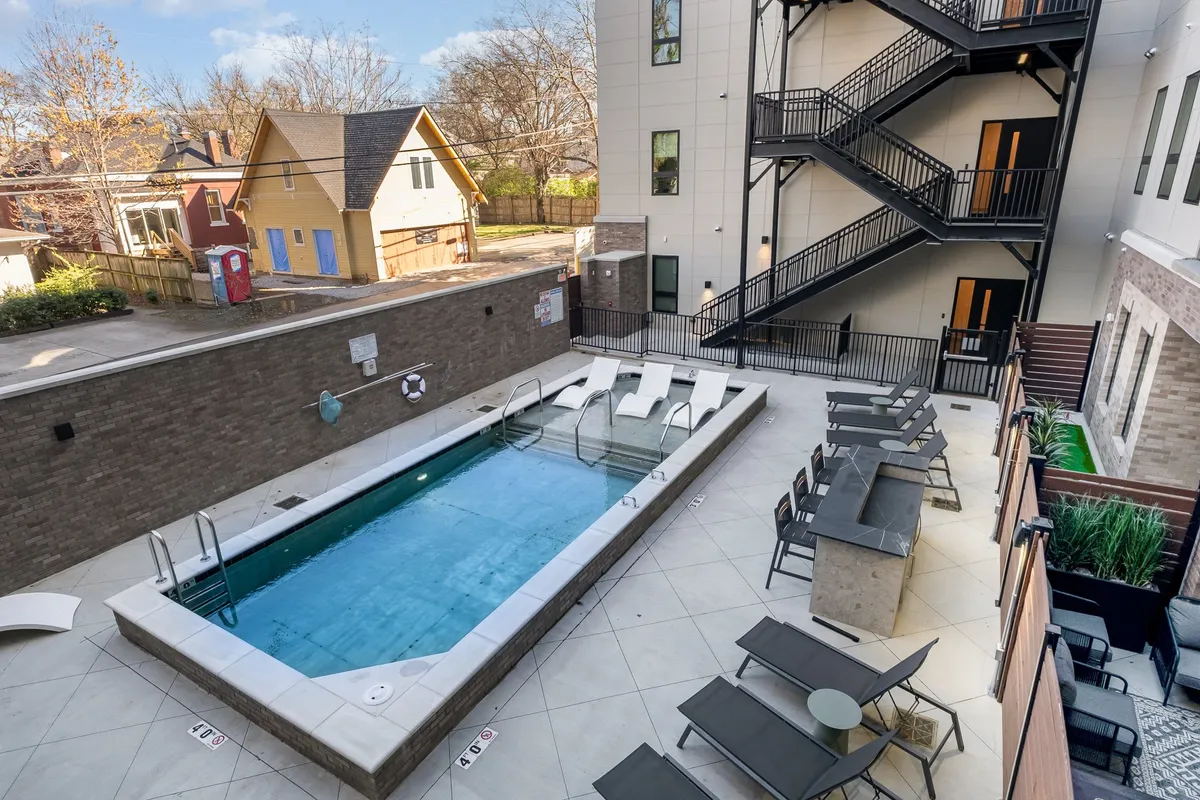 An inviting outdoor swimming pool area with lounge chairs, an outdoor seating arrangement, and a staircase. The atmoshpere is relaxed and social, suggesting both sunbathing and group gatherings at the poolside, with a hint of sunset lighting.