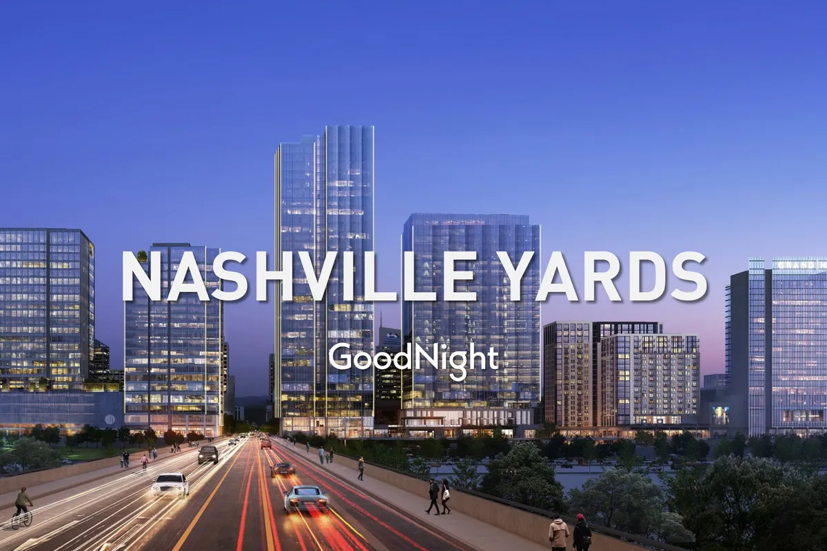 A dynamic nighttime shot of Nashville Yards featuring towering skyscrapers, illuminated buildings, and a lively urban street scene. The area is bustling, with light and energy highlighting its role as a hub for business and entertainment in downtown Nashville.